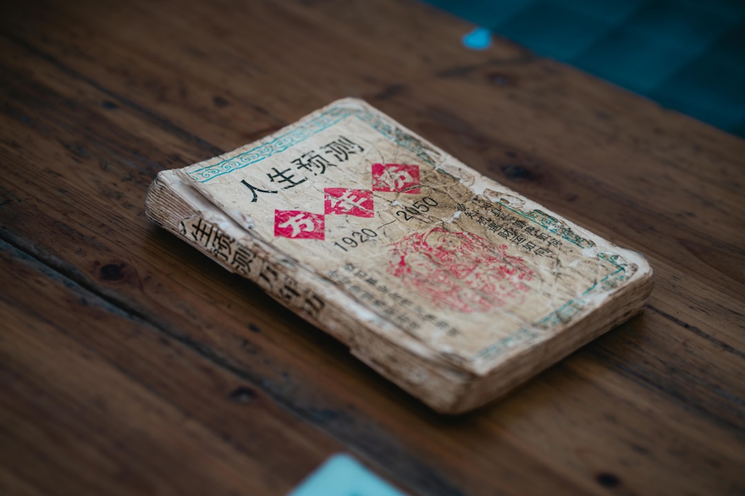 An old book with chinese characters rests on wood.