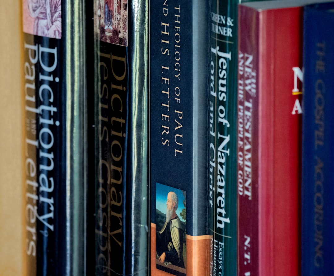 Books about jesus and the bible are on a shelf.