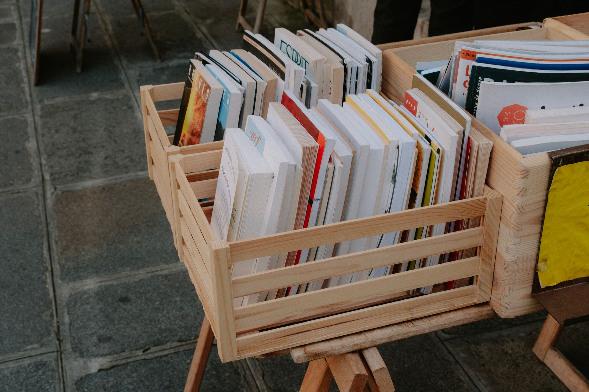 Close-up of books arranged in wooden crates at an outdoor market, emphasizing literature and reading.