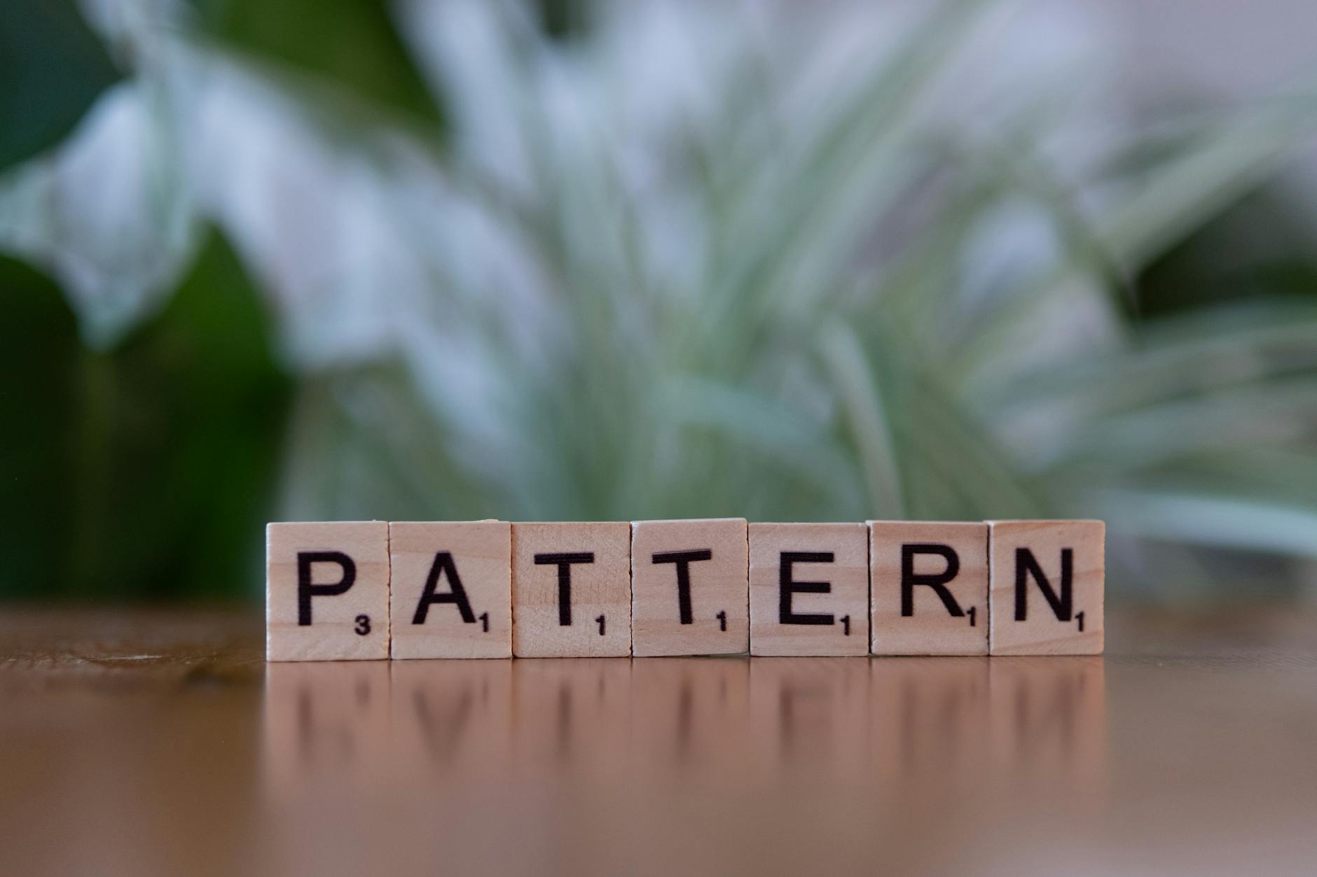 Scrabble tiles spelling 'Pattern' on a wooden surface with a soft-focus background.