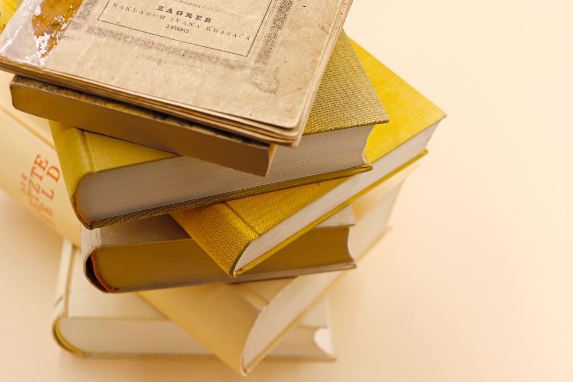 A collection of antique books stacked on a warm cream background, showcasing vintage charm and historical intrigue.