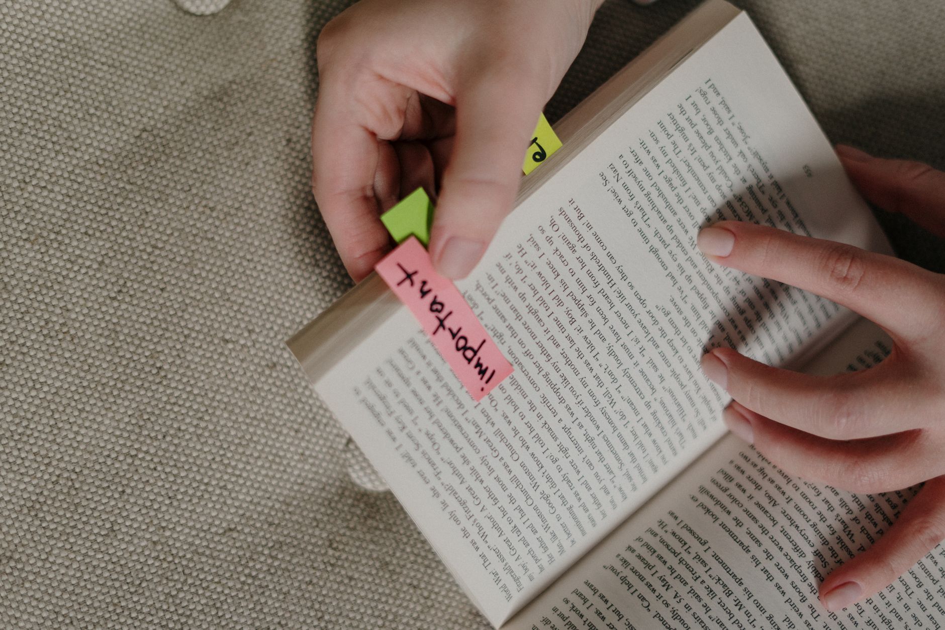 A close-up image of hands marking a book with colorful sticky notes for emphasis.