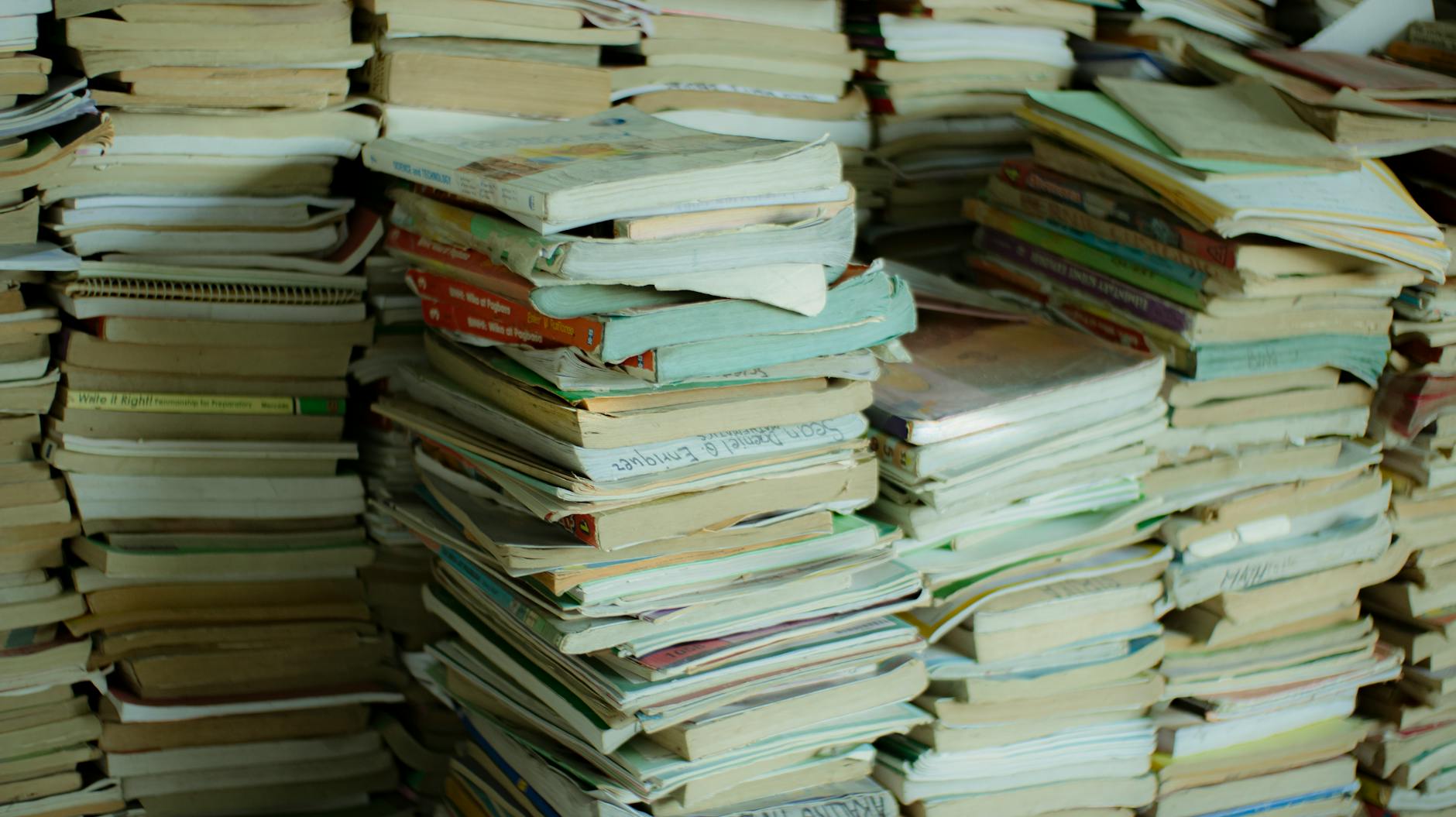 A towering stack of old books in a dimly lit room creating a literary labyrinth.