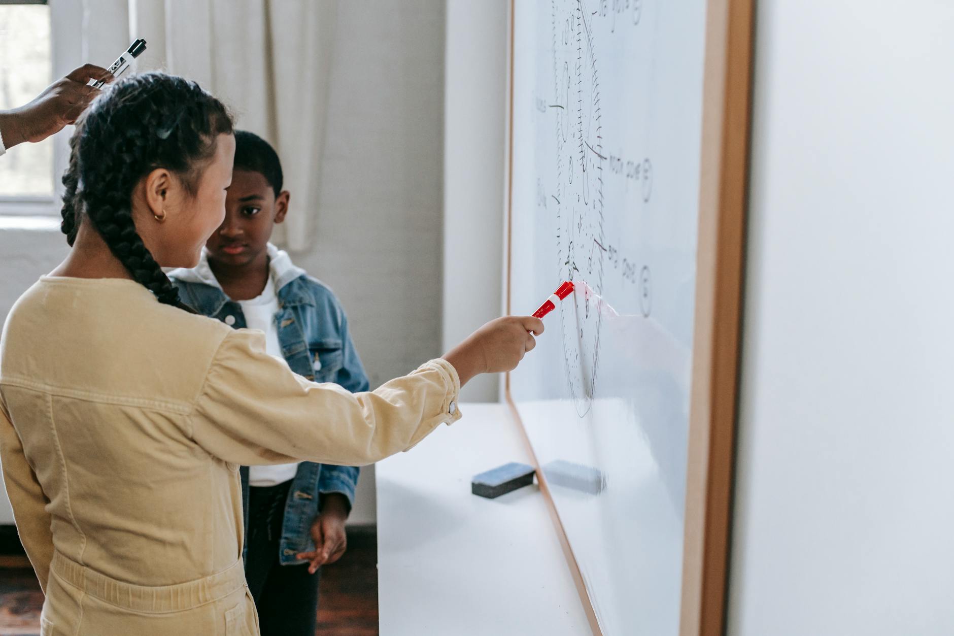 Diverse smart teenagers answering questions of teacher and listening near whiteboard in class