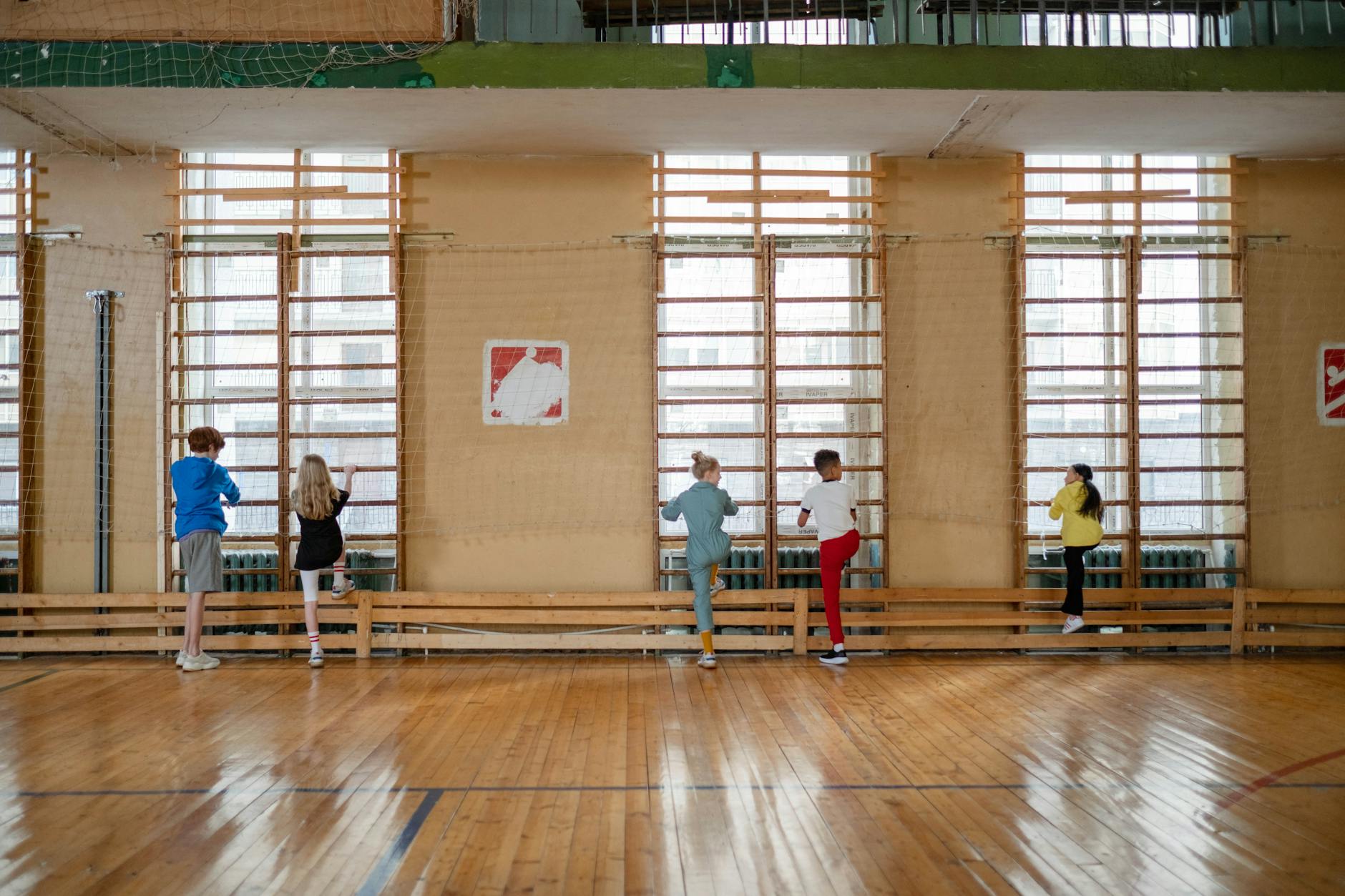 Kids enjoying a fun climbing activity in a school gym, practicing teamwork and physical education.