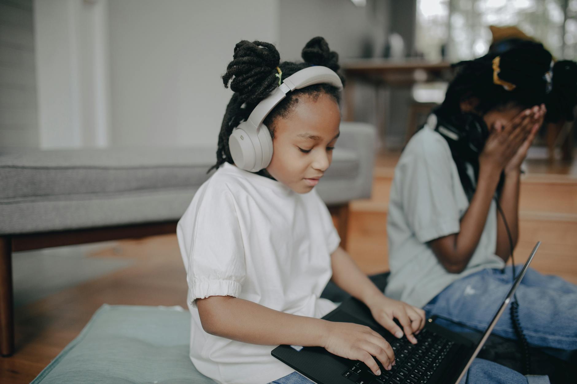 African American girl with headphones using a laptop at home.