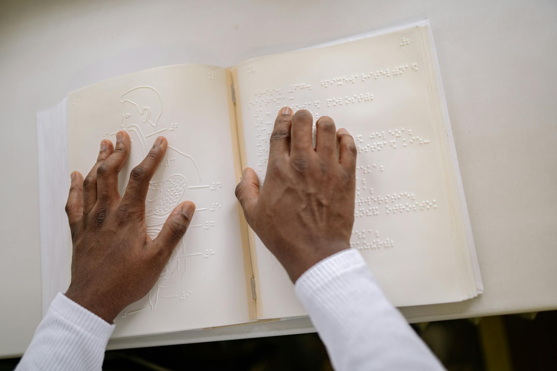 Hands touching braille text, focusing on tactile reading and accessibility for visually impaired individuals.