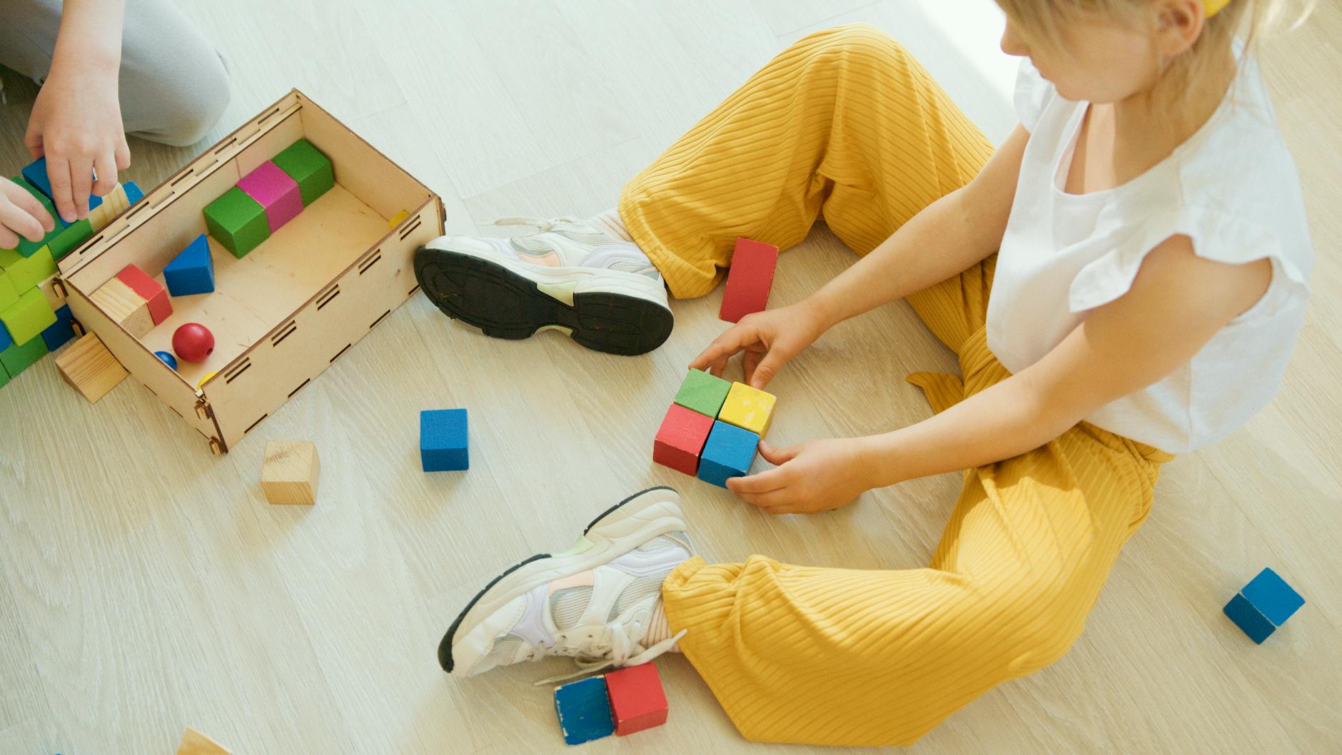 A young child playing creatively with colorful wooden blocks indoors, fostering learning and development.