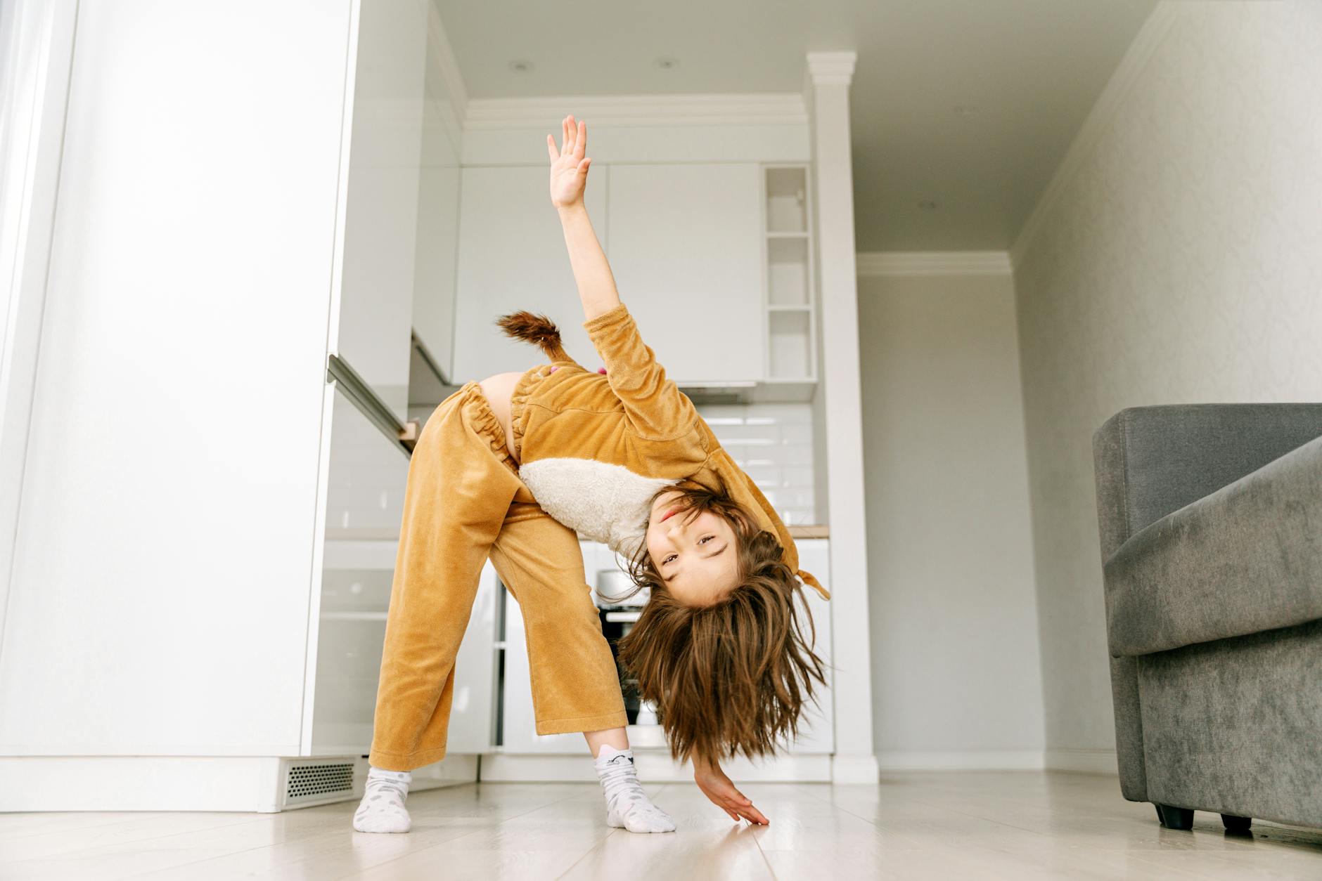 A playful child in animal pajamas having fun in a modern living room.