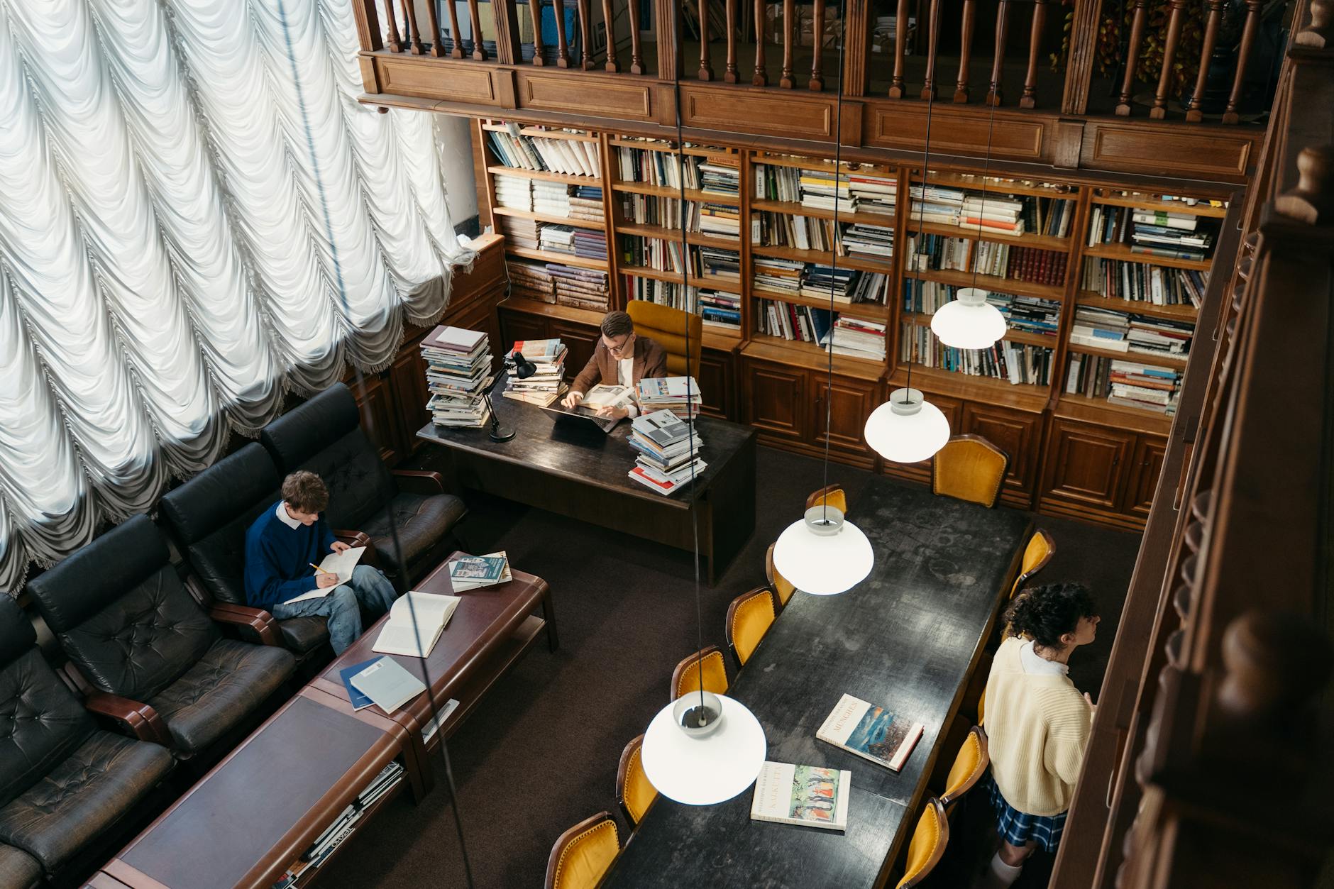 Aerial view of a cozy library with people reading and studying, surrounded by bookshelves.