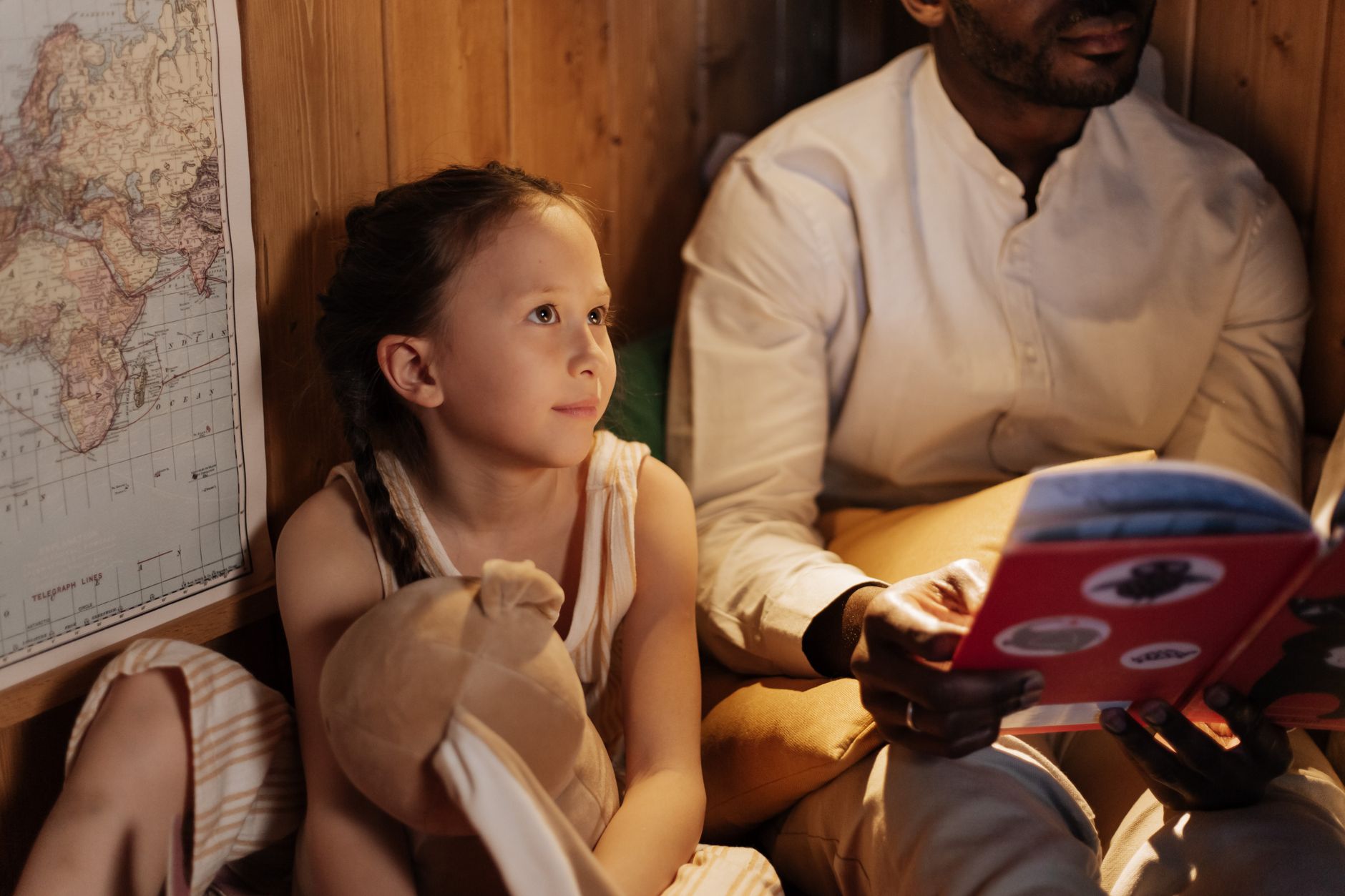 A father reading a bedtime story to his daughter at home, fostering family bonds.