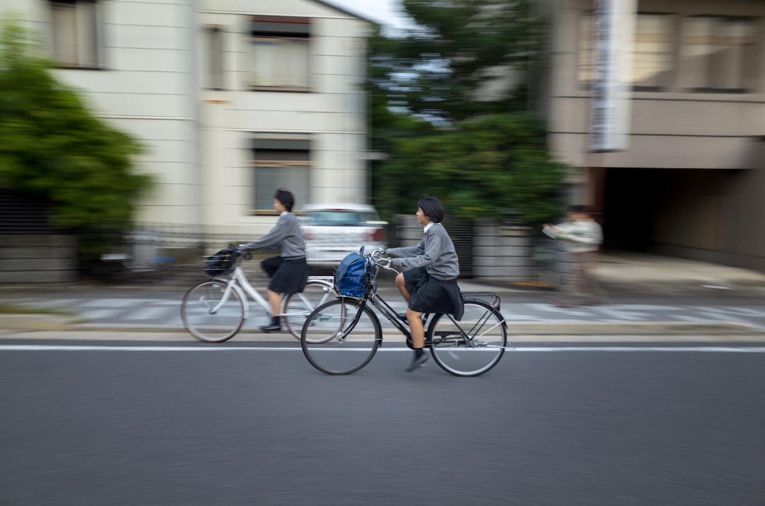 Two students cycle past buildings in motion blur
